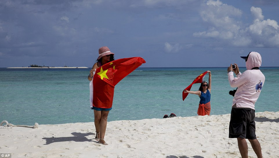 Very patriotic: Tourists pose with Chinese flags on one of the Paracel Islands in the disputed South China Sea