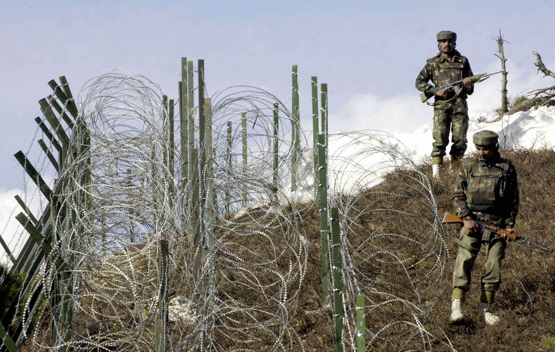 Indian soldiers as they patrol along a barbed-wire fence near Baras Post