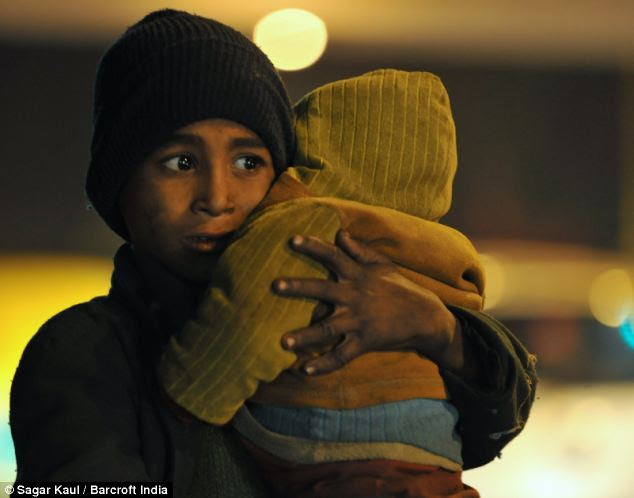 A homeless boy holds his little brother close on a footpath in New Delhi