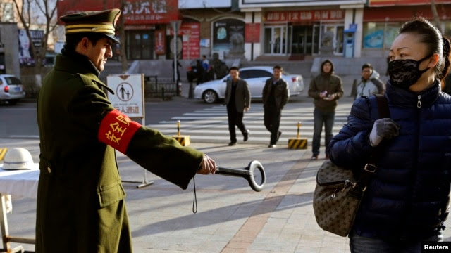 Cảnh sát Trung Quốc giơ máy dò kim loại vào một phụ nữ đi bộ trên đường phố ở Urumqi, Tân Cương.