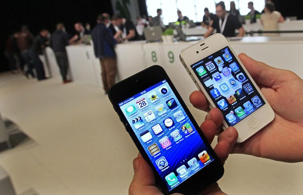 Usuário compara a nova versão do smartphone (à esquerda) com o iPhone 4S durante o lançamento do aparelho em Bruxelas. O novo iPhone está mais comprido, leve e fino. (Foto: Yves Herman/Reuters)