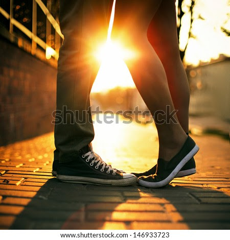 Young couple kissing outdoor in summer sun light. Kiss love date color evening teen. - stock photo