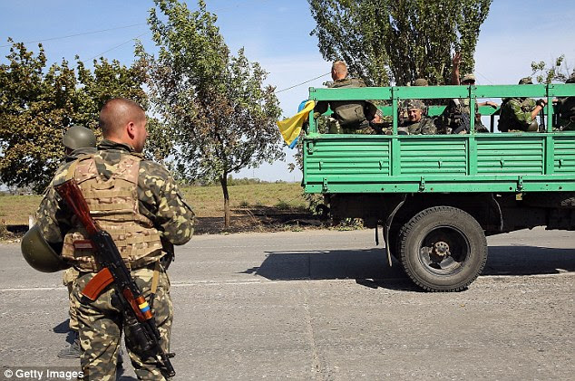 Ukrainian soldiers head to a frontline position in Mariupol on the back of a truck