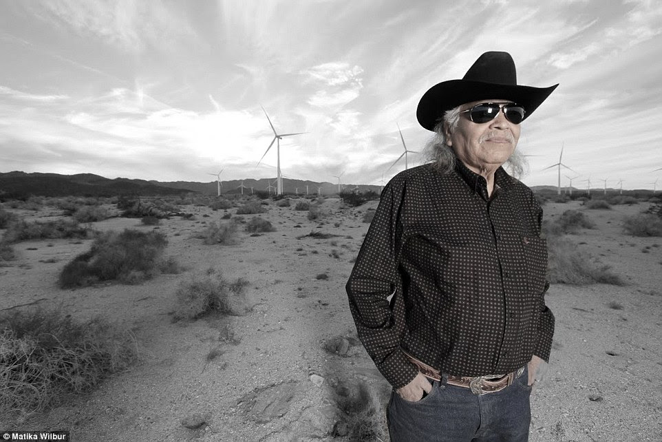 Juxtaposing modernity and history, Matika's photo depicts an indigenous American stands in front of a farm of wind turbines, looking out at the landscape