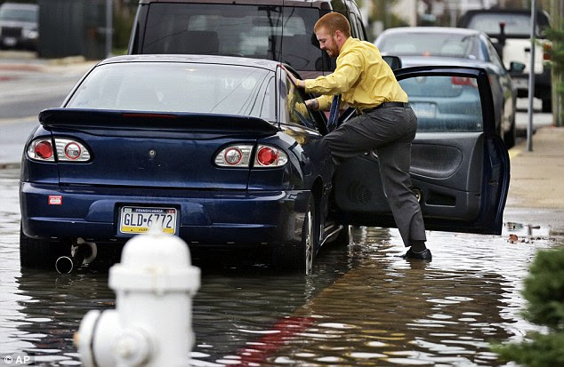 Cody Billotte walks through the high water as he loads his car to go to work as Hurricane Sandy bears down on the East Coast, Sunday, Oct. 28, 2012, in Ocean City, Maryland 