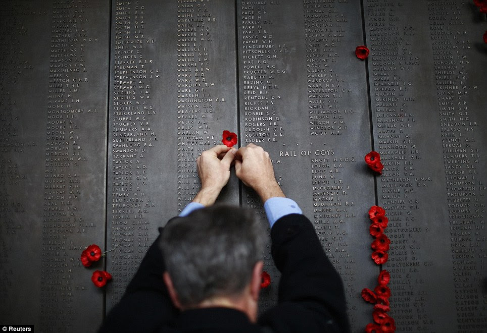 A man places a poppy flower into the World War I Wall of Remembrance on ANZAC Day at the Australian National War Memorial in Canberra this morning