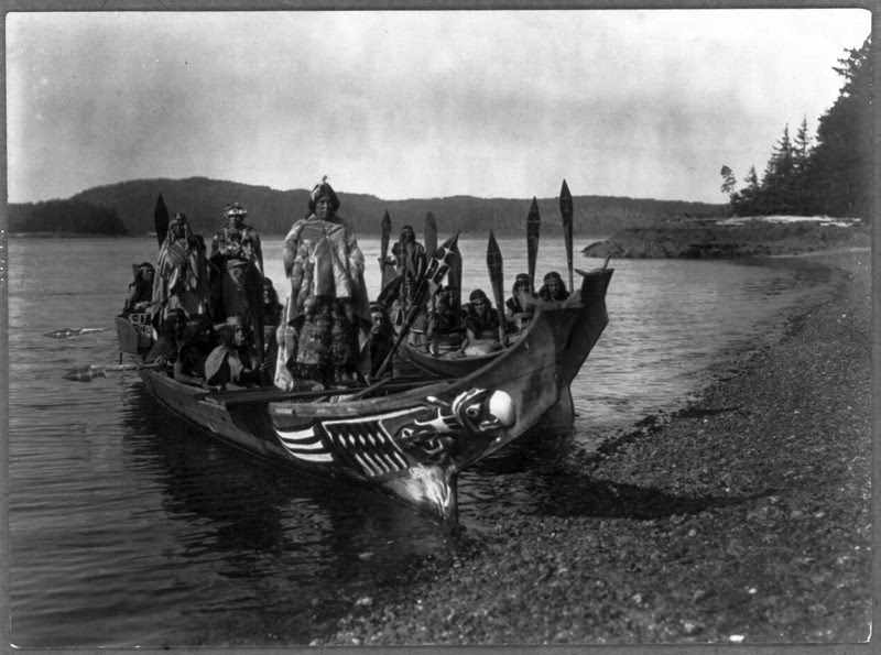 Description of  Title: The wedding party--Qagyuhl.  <br />Date Created/Published: c1914 November 13.  <br />Summary: Two canoes pulled ashore with wedding party, bride and groom standing on "bride's seat" in the stern, relative of the bride dances on platform in bow.  <br />Photograph by Edward S. Curtis, Curtis (Edward S.) Collection, Library of Congress Prints and Photographs Division Washington, D.C.