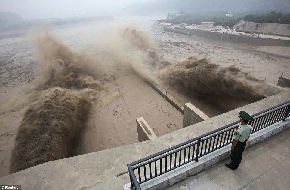 The lone soldier stands guard as sediment-laden flood water gushes through the Xiaolangdi Dam, unleashing tons of water