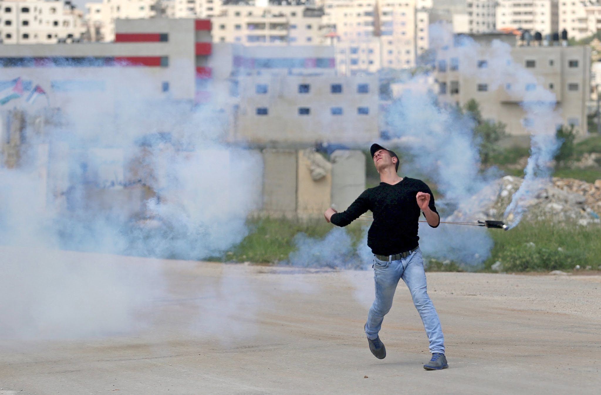 A Palestinian protester uses a sling to return a tear gas canister fired by Israeli troops during clashes at a protest marking Land Day, near Israel's Ofer Prison near the West Bank city of Ramallah March 30, 2016. March 30 marks Land Day, the annual commemoration of protests in 1976 against Israel's appropriation of Arab-owned land in the Galilee