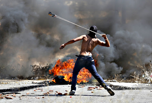 Palestinian protester uses a sling to hurl stones towards Israeli troops during clashes near the Jewish settlement of Bet El, near the occupied West Bank city of Ramallah...A Palestinian protester uses a sling to hurl stones towards Israeli troops during clashes near the Jewish settlement of Bet El, near the occupied West Bank city of Ramallah October 5, 2015. Violence intensified in Jerusalem and the West Bank on Sunday after Israelis were targeted in two stabbing attacks and a Palestinian was killed in a clash with Israeli troops, officials said