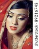 Portrait of young beautiful happy indian bride with bright makeup and golden jewelry - stock photo