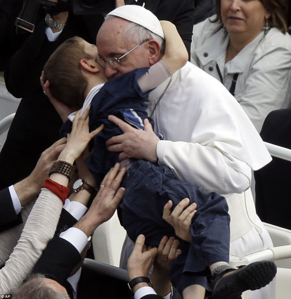 Caring: Pope Francis hugs a child during the Easter Sunday celebrations