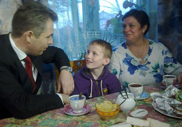 Artem now calls Vera Egorova, right, Mama. She and her husband hope to adopted him and five other children they have been fostering. The Kremlin's tsar for children, Pavel Astakhov, left, has a special interest in Artem's case and makes periodic visits