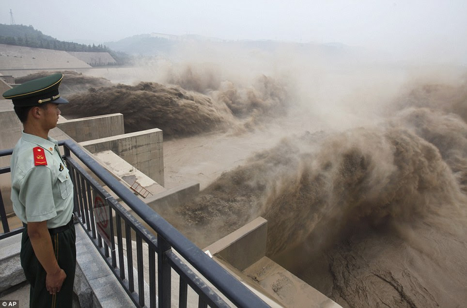 Floods in China: A paramilitary policeman watches water carrying silt gushing out of three specialised holes in the dam of the Xiaolangdi Reservoir on the Yellow River during the annual silt-washing operation