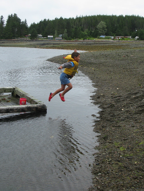 a boy jumps to shore at low tide, Kasaan, Alaska