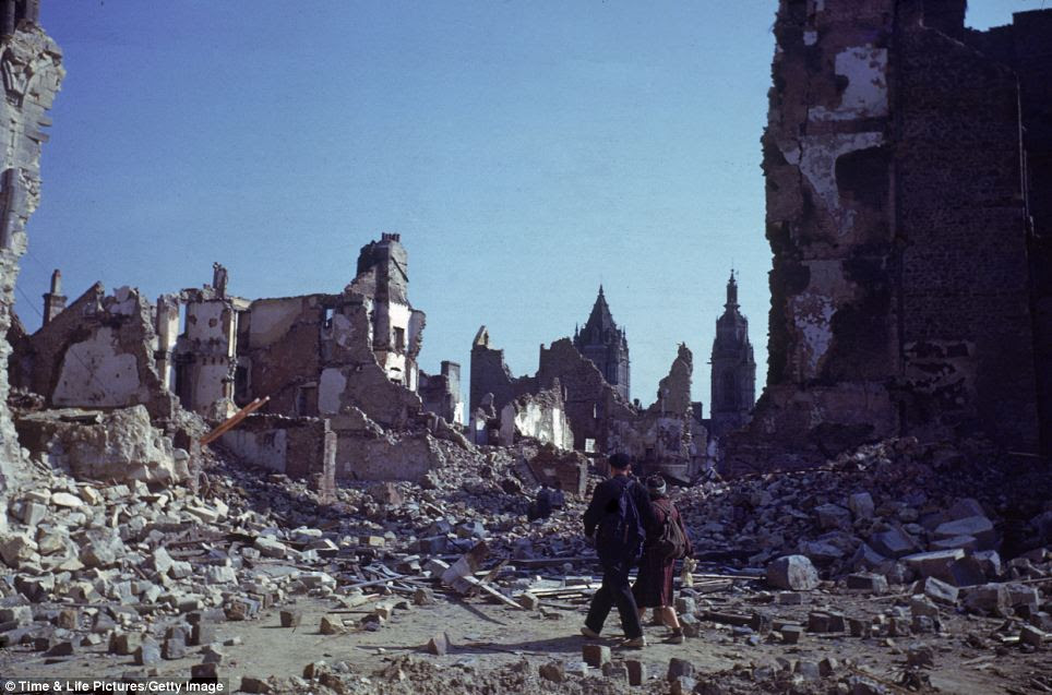 A civilians couple walk through ruins of the heavily bombed ruins in the city of St. Lo, France, August 1944