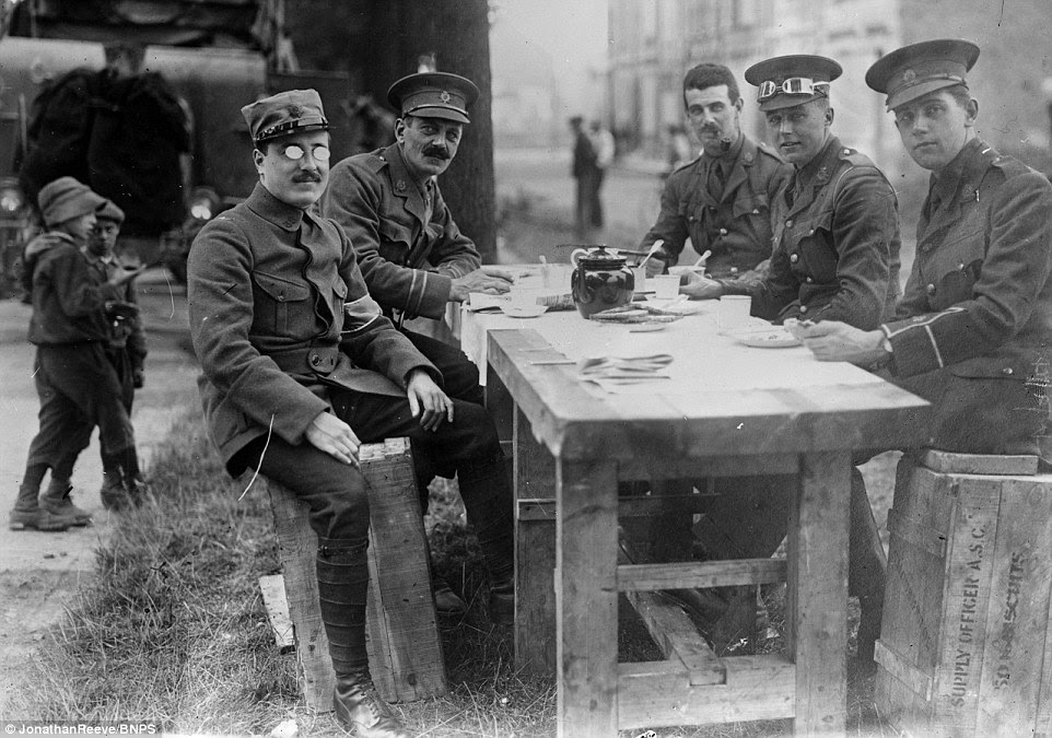 A French officer has tea at a table with English Tommies behind the lines on the Western Front during the First World War