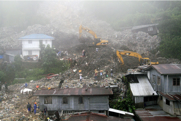 Rescuers and volunteers try to clear piles of garbage under thick fog in Baguio City, northern Philippines on Monday Aug. 29, 2011. Several tons of garbage buried some shanties after a dumpsite's conc