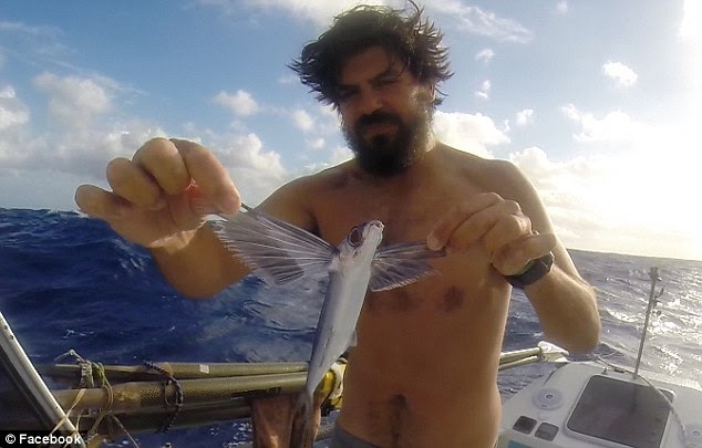 Awe-inspiring: Manser holds up a flying fish he caught while crossing the Atlantic