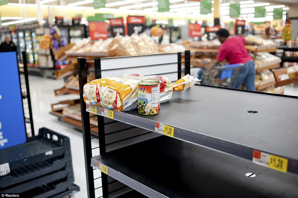 A woman shops for groceries amid an empty shelf of bread as people prepare for Hurricane Sandy at a Walmart store in Virginia Beach, Virginia today