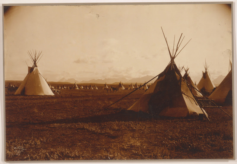 Description of  Title: Piegan encampment.  <br />Date Created/Published: c1900.  <br />Summary: Tepees with mountains in background.  <br />Photograph by Edward S. Curtis, Curtis (Edward S.) Collection, Library of Congress Prints and Photographs Division Washington, D.C.