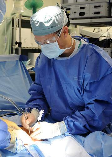Navy doctor prepares to insert an endoscope through a patient's belly button before performing surgery