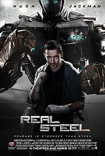 Hugh Jackman in character in a boxing pose in front of a large boxing robot in a similar pose.