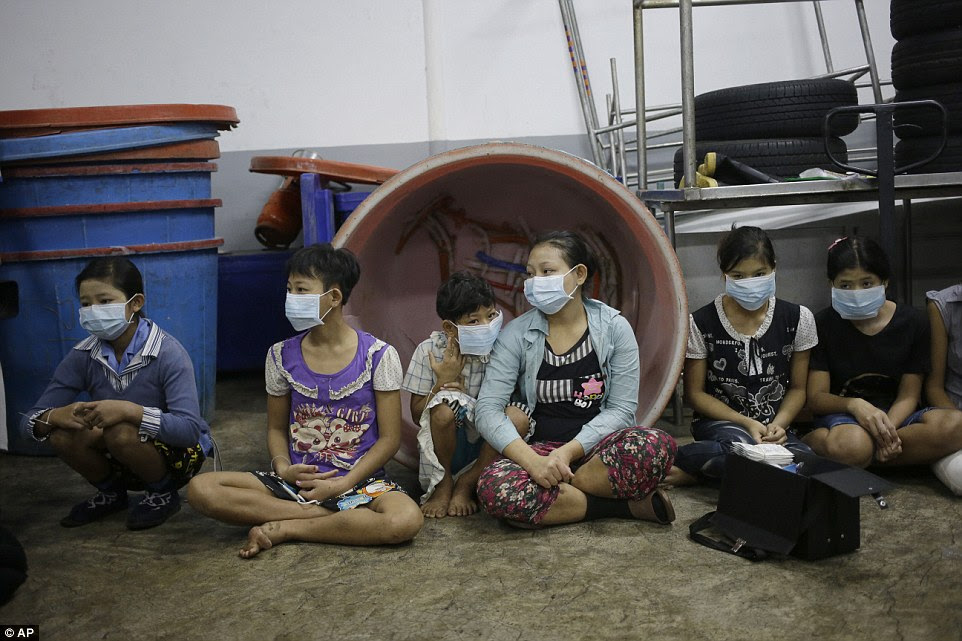 Trafficked: Children sit together to be registered by officials during a raid on a shrimp shed in Samut Sakhon, Thailand. Abuse is common in Samut Sakhon, which attracts workers from some of the world's poorest countries, mostly from Myanmar, to peel seafood