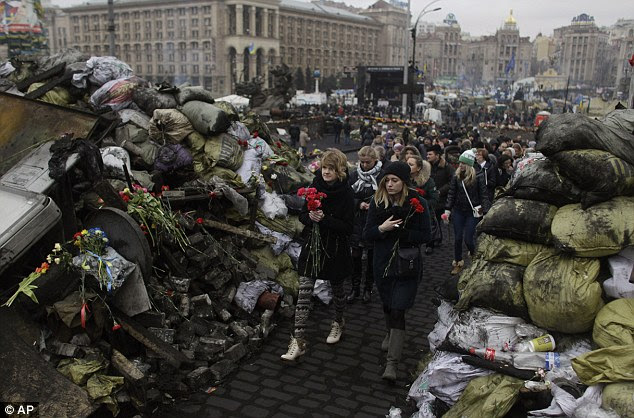 Women holding flowers pass by barricades in Kiev's Independence Square, the epicenter of the country's current unrest, Ukraine