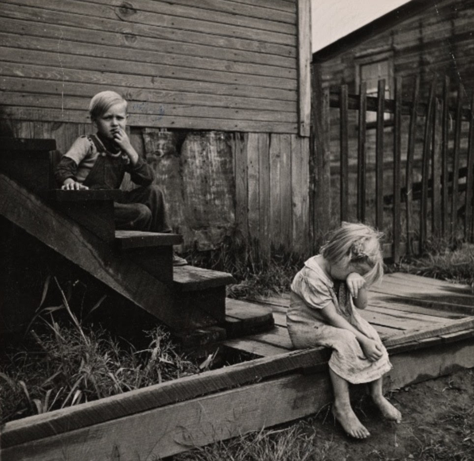 Children sitting on the steps of a dilapidated house in Michigan in June of 1937