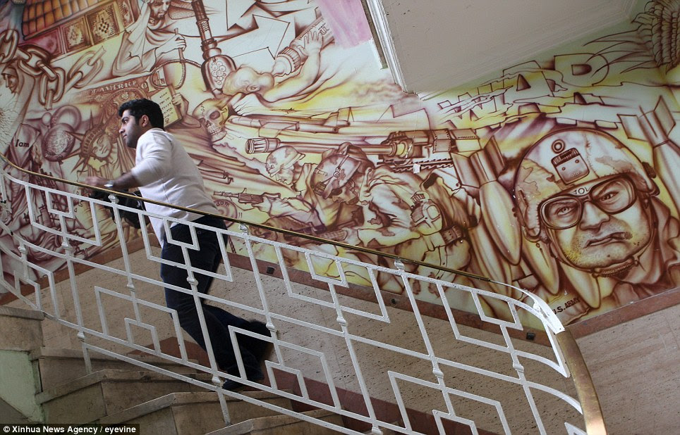 Art as protest: An Iranian Journalist climbs the stairs inside the former US embassy in downtown Tehran. Painted on the walls are anti-American murals