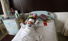 The boy lies on his hospital bed