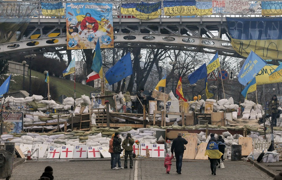 Curiosos observam barricada montada por opositores ao presidente da Ucrânia, Viktor Yanukovich, na Praça da Independência em Kiev. Milhares de manifestantes tem se reunido no local para protestar contra o governo, por se afastar cada vez mais da UE