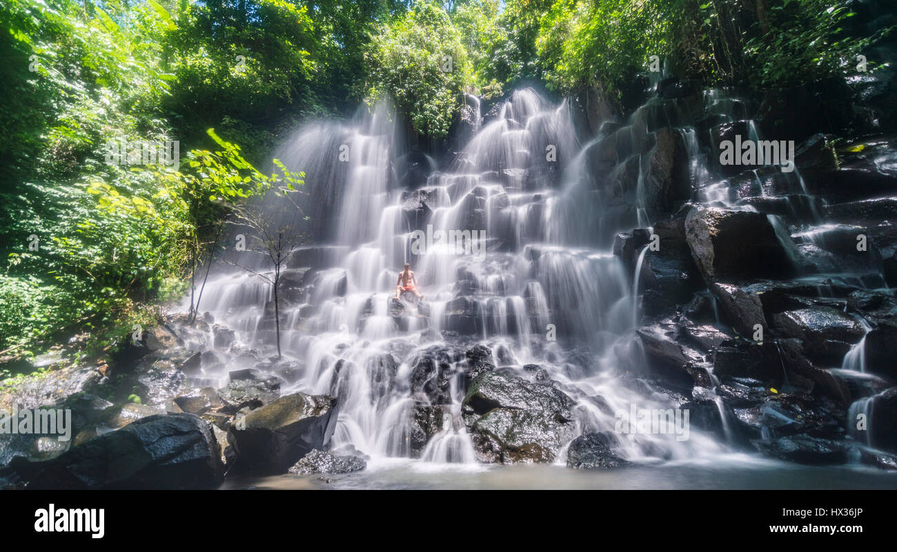Man sitting in a waterfall Air Terjun Kanto Lampo in Ubud Man sitting in a waterfall Air Terjun Kanto Lampo in Ubud