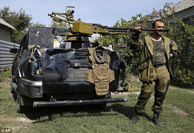 A pro-Russian rebel, armed with a heavy machine gun, stands next to his car