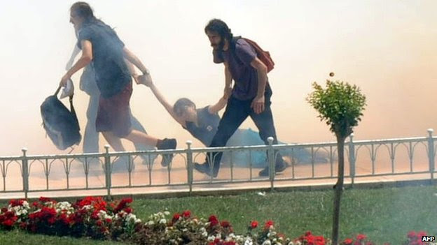 Demonstrators help one another as Turkish riot policemen use tear gas to disperse clashes (May 31, 2013)