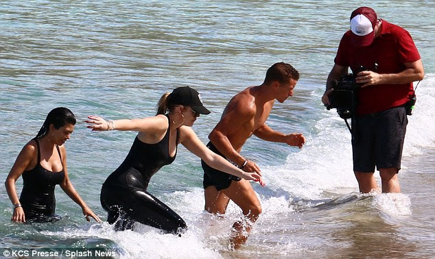 Hard at work: Kim's sisters Kourtney and Khloe took a fully clothed dip as they got in some exercise on the beach 