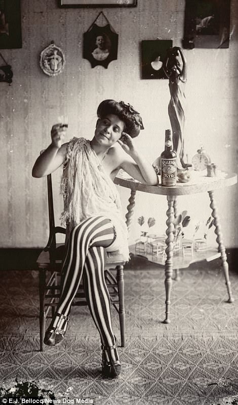 A seated woman wearing striped stockings and drinking Raleigh Rye in Storyville, New Orleans, circa 1912. Storyville was the only legalised red-light district in a major city in North America, until it was shut down in 1917