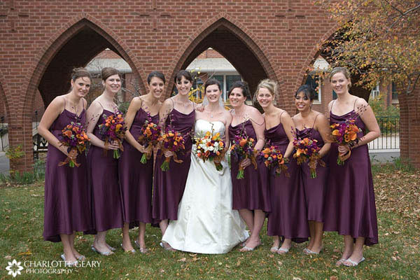 Bridesmaids in purple dresses with orange and purple flowers