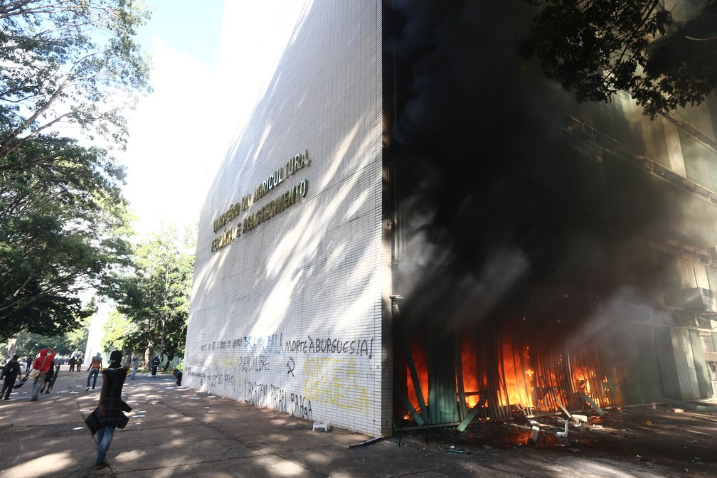 Manifestantes que protestam nesta quarta-feira contra as reformas e pela renúncia do presidente Michel Temer colocaram fogo no prédio do Ministério da Agricultura, em BrasÃlia. Carros do Corpo de Bombeiros, Samu e caminhão pipa já estão no local para controlar a situação. Enquanto bombeiros se aproximam, manifestantes jogam pedaços de pau e uma pessoa se feriu no rosto (Foto: Wilton Junior/Estadão Conteúdo)