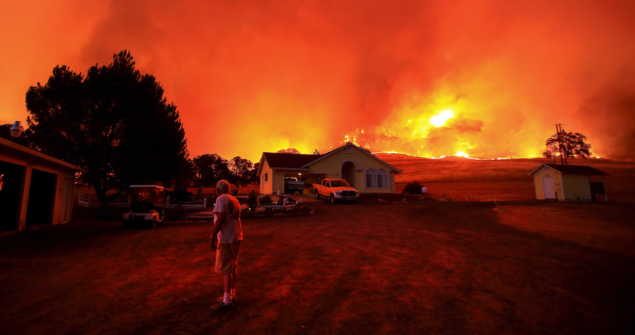 A wall of flames lurches over a ridge as a resident of Morgan Valley Road near Lower Lake, California, prepares to evacuate because of the 3,000 acre Rocky Fire that has taken hold in Lake County.