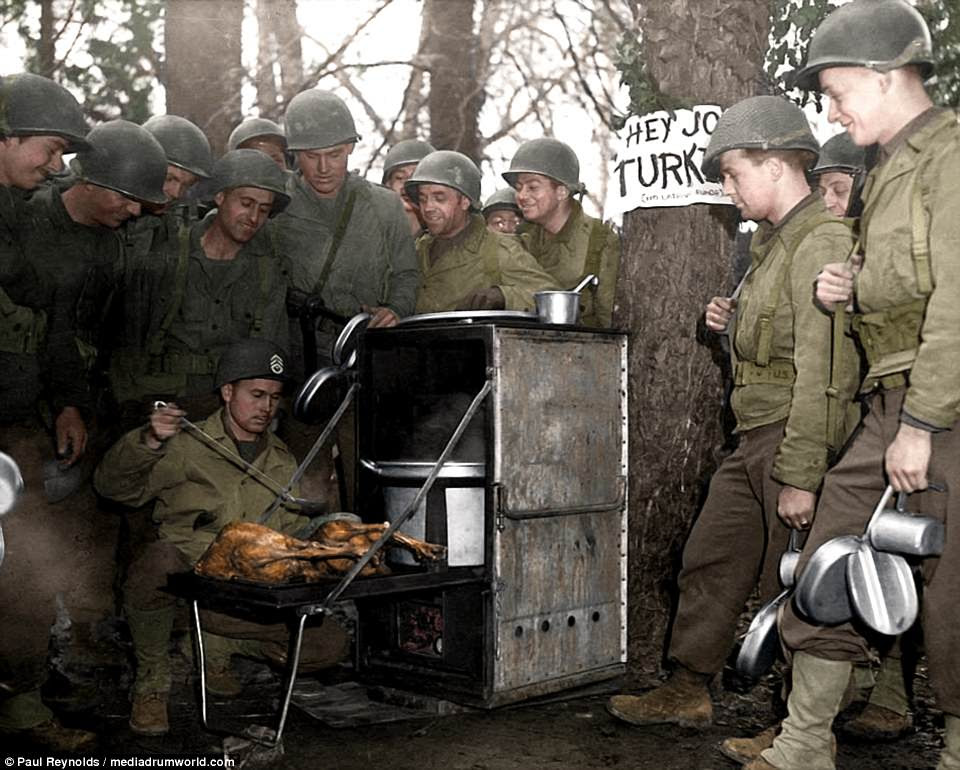 Dinner time: US troops huddle around a M1937 Field Range cooker while Sgt Louis S. Wallace of Meadville, Mississippi prepares turkey for Thanksgiving. It is not clear where or when the image was captured