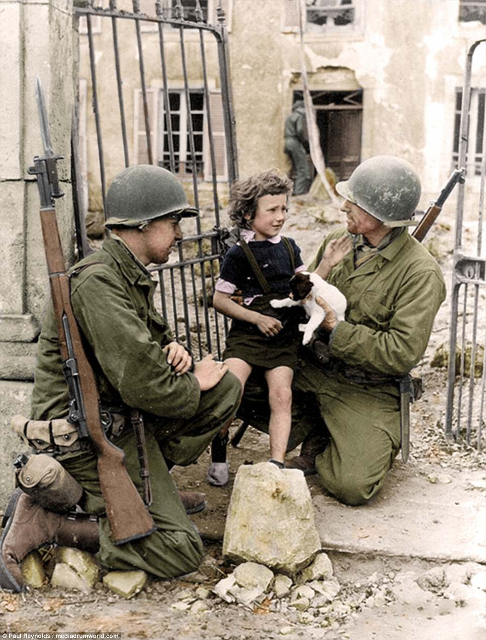 Soldiers comfort a girl with a puppy in Colleville-sur-Mer, France, which is now the site of the Normandy American Cemetery and Memorial. The memorial in the commune replaced a temporary cemetery established by the US First Army in June 1944