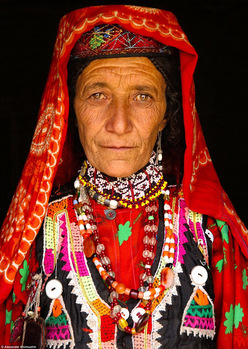 Um retrato de uma mulher Wakhi (foto) vestido com uma roupa vermelha brilhantemente colorida, marcada com uma infinidade de padrões e texturas representa os habitantes do Corredor Wakhan no nordeste do Afeganistão