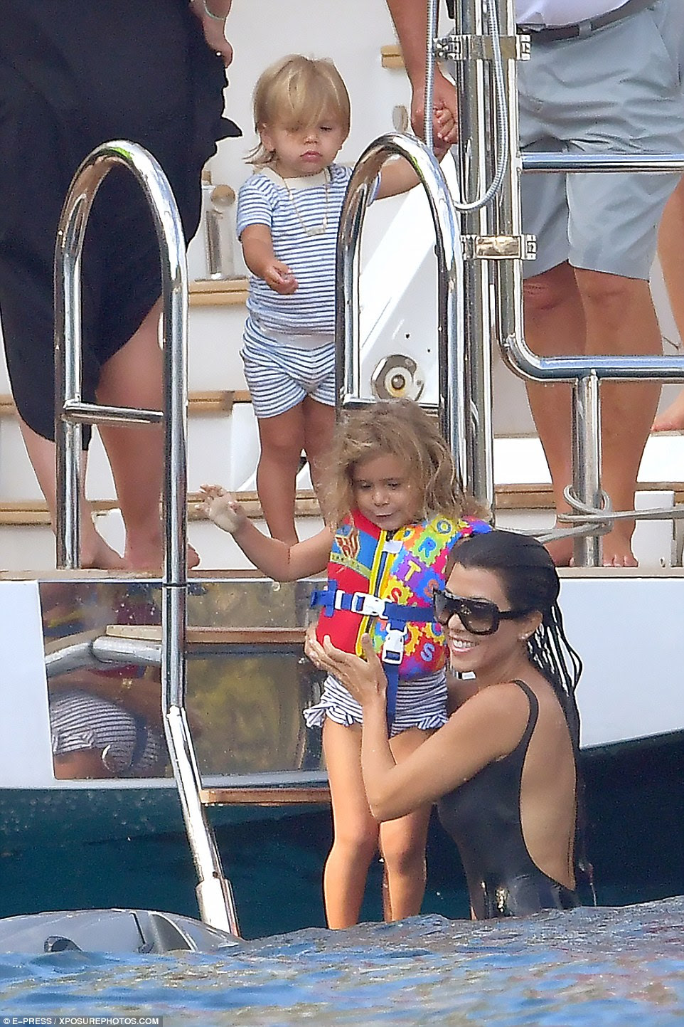 All smiles: Kourtney helped Penelope into the water as son Reign looked on