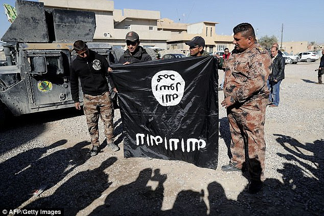The woman, a 'biter' for the Islamic State, was ambushed in a suspected revenge attack in Kirkuk. Pictured: Iraqi soldiers, who are advancing on the group's territory, with a captured Islamic State flag