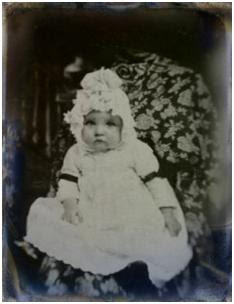 C19th tintype image of baby in mourning and wearing black armband ribbons.