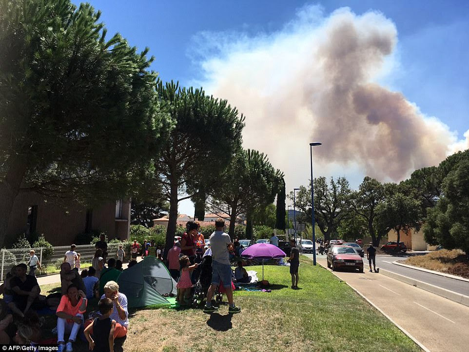 Tourists sheltered from the sun under trees after being evacuated from villas, hotels and campsites in fire-hit Bormes-les-Mimosas