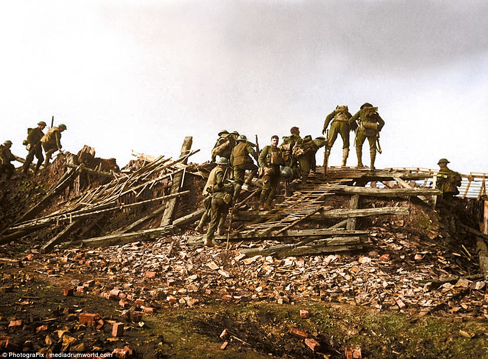 Carrying heavy packs and metal helmets, a group of British soldiers continue their journey across a landscape littered with  debris