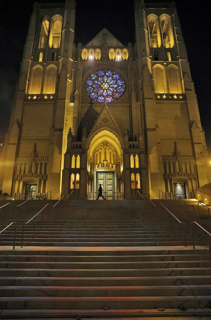 A pedestrian walks by the front of Grace Cathedral in San Francisco, Calif., on Monday, November 23, 2015. Grace Cathedral has a new look now that the stained glass rose is lighted by a daylight balanced spotlight allowing all the correct colors to be visible. In addition, two spotlights in the arcade above the rose window project colors onto the cathedral's steps. Photo: Carlos Avila Gonzalez, The Chronicle